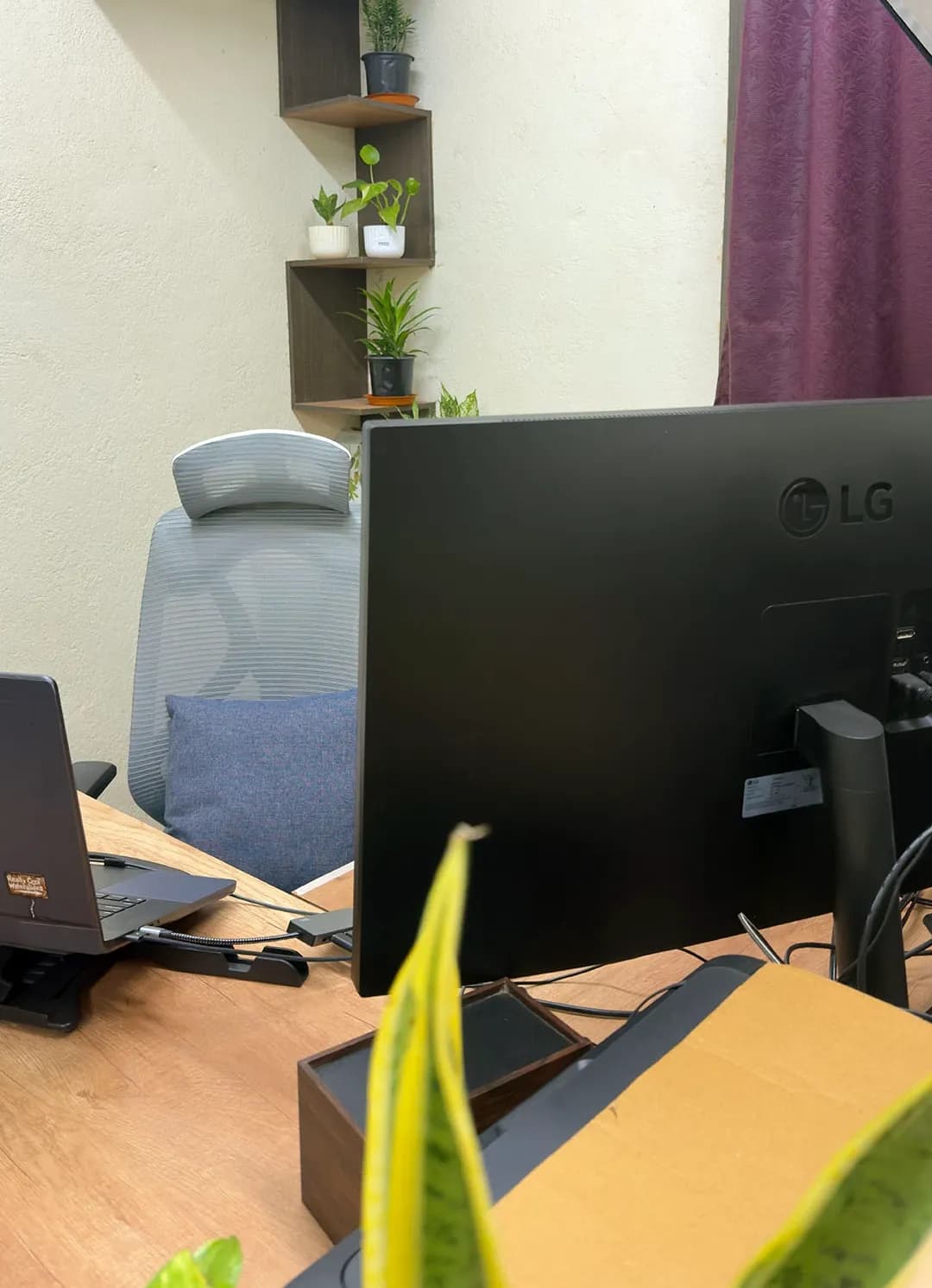 The back of an LG monitor and a laptop facing a grey office chair, Kolkata, India
